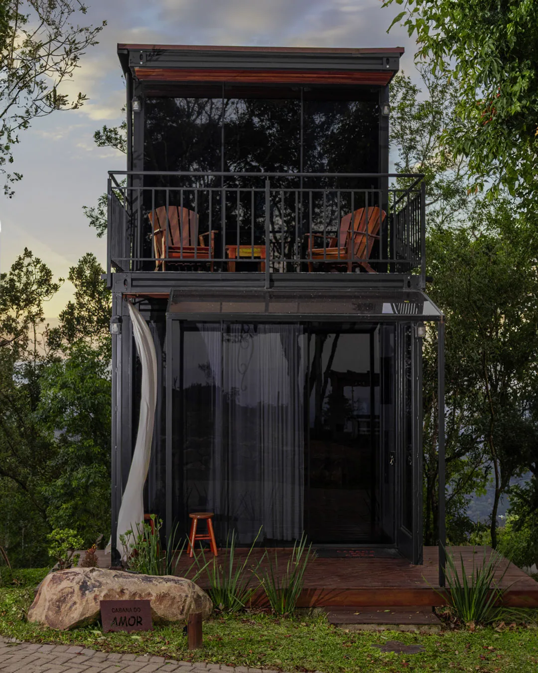 Cabana do Amor — fachada de vidro entre as árvores, com varanda